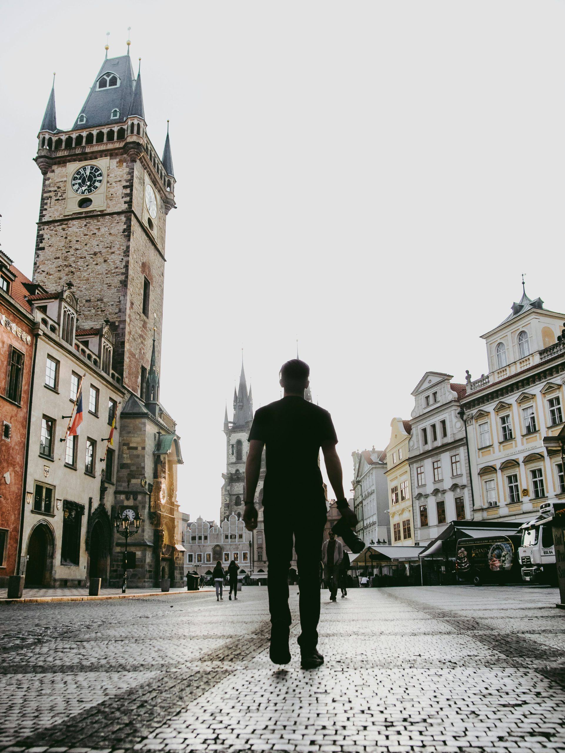 Person walking alone across an old town square at dawn